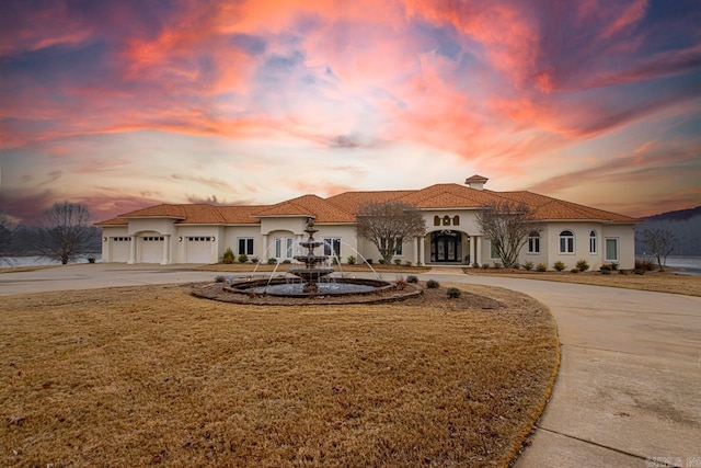 mediterranean / spanish-style house with a garage and a lawn