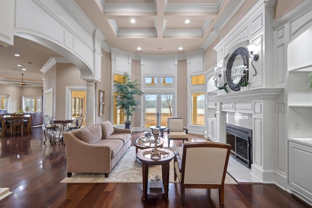 living room with hardwood / wood-style flooring, a premium fireplace, beam ceiling, a high ceiling, and coffered ceiling