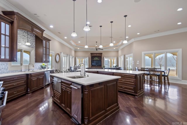 kitchen featuring hanging light fixtures, dark brown cabinets, a kitchen island with sink, and sink