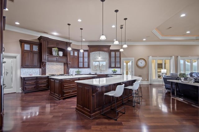 kitchen with a breakfast bar area, a center island, dark hardwood / wood-style floors, pendant lighting, and backsplash