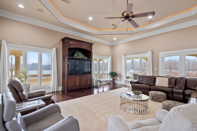 living room with dark wood-type flooring, ornamental molding, a raised ceiling, and french doors