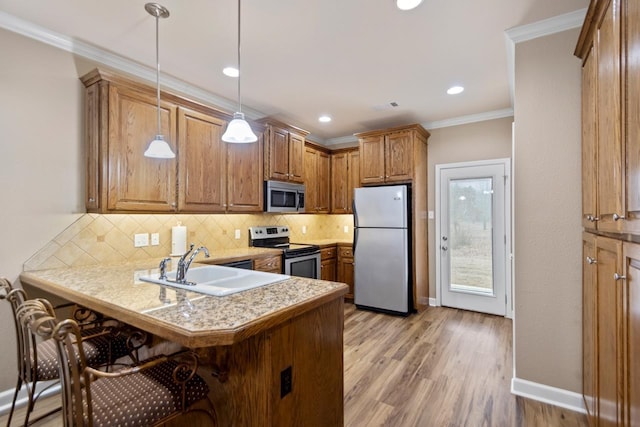 kitchen with appliances with stainless steel finishes, a breakfast bar, hanging light fixtures, kitchen peninsula, and crown molding