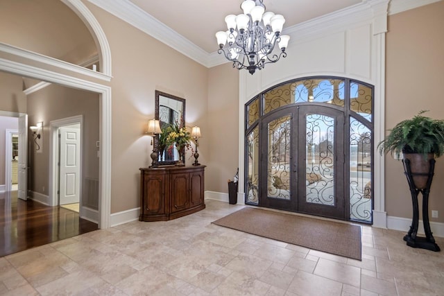 foyer entrance featuring an inviting chandelier, crown molding, french doors, and a towering ceiling