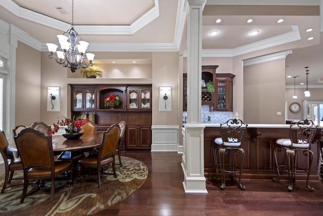 dining area with a raised ceiling, ornamental molding, dark hardwood / wood-style floors, and ornate columns