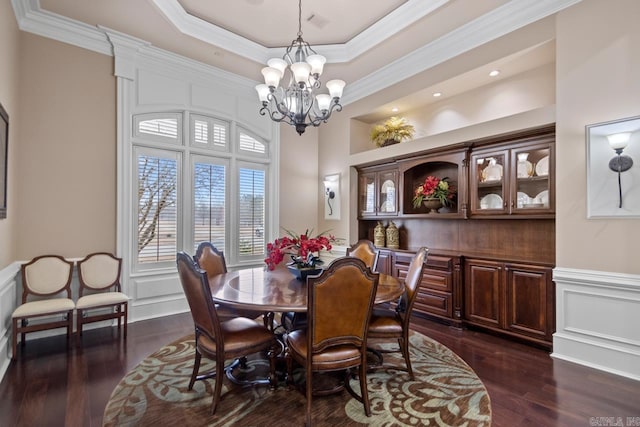 dining space featuring a notable chandelier, crown molding, dark wood-type flooring, and a raised ceiling