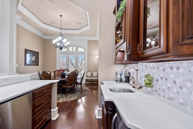 kitchen featuring crown molding, sink, a tray ceiling, and hanging light fixtures