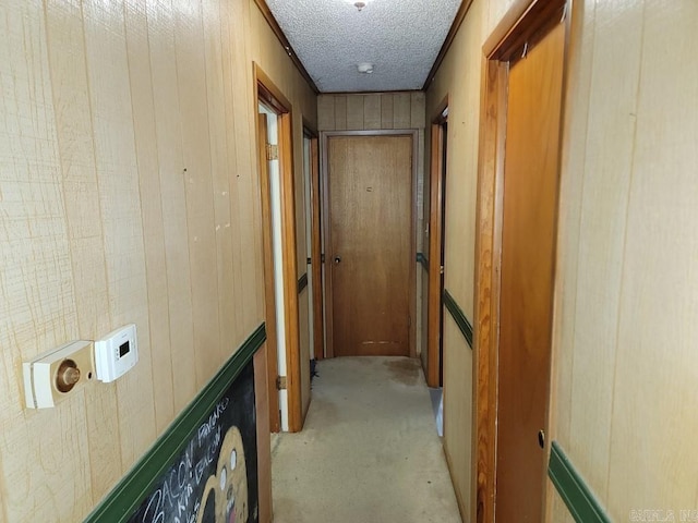 hallway featuring a textured ceiling and wood walls