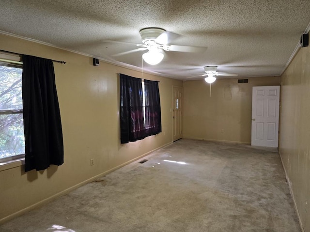 empty room featuring ceiling fan, a healthy amount of sunlight, light colored carpet, and a textured ceiling