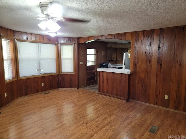 kitchen with hardwood / wood-style floors, a textured ceiling, and wood walls