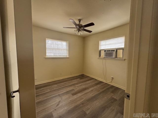 empty room featuring dark wood-type flooring, cooling unit, and ceiling fan