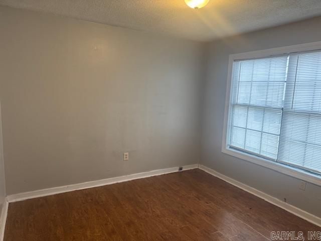 empty room featuring dark hardwood / wood-style floors and a textured ceiling