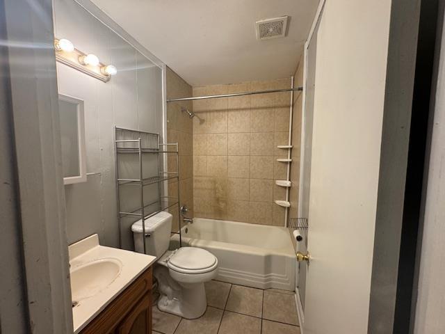 full bathroom with tile patterned flooring, vanity, tiled shower / bath combo, and toilet