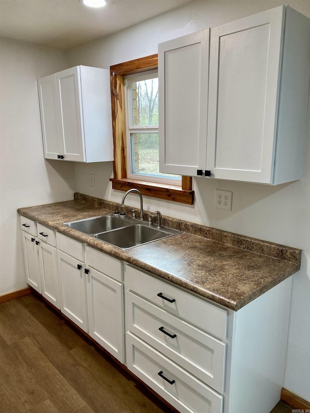 kitchen featuring dark wood-type flooring, sink, and white cabinets