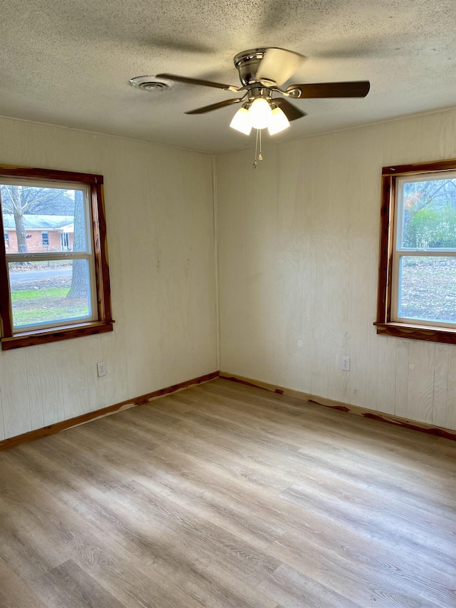 unfurnished room with a wealth of natural light, a textured ceiling, and light hardwood / wood-style flooring