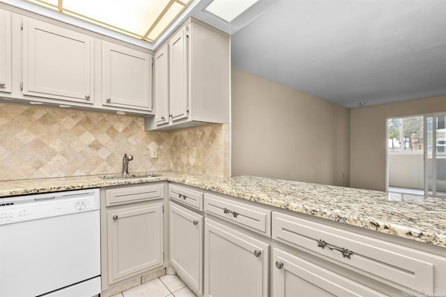 kitchen featuring sink, dishwasher, a skylight, light tile patterned flooring, and decorative backsplash