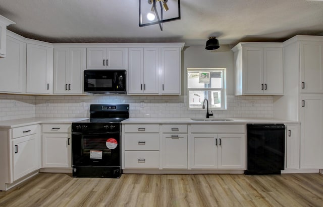 kitchen with sink, black appliances, light hardwood / wood-style floors, and white cabinets