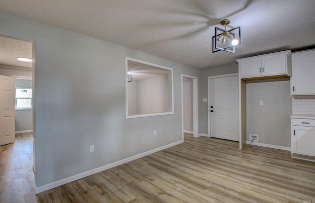 kitchen featuring a textured ceiling, white cabinets, and light hardwood / wood-style floors