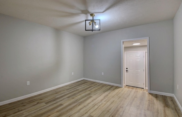 empty room with light hardwood / wood-style floors and a textured ceiling