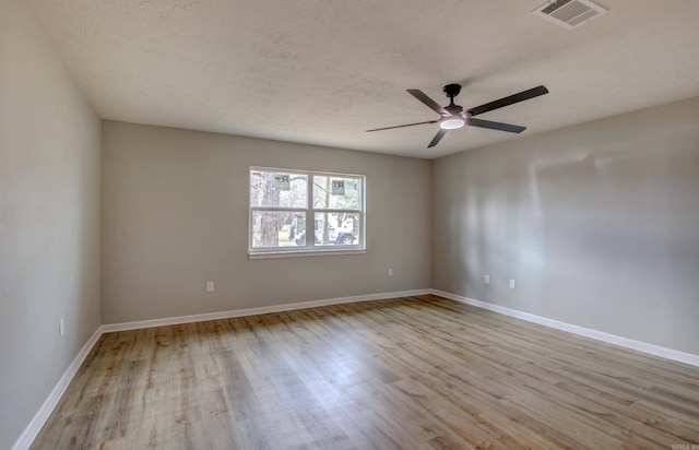 unfurnished room with ceiling fan, a textured ceiling, and light wood-type flooring