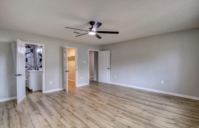 unfurnished bedroom featuring ceiling fan, a spacious closet, light hardwood / wood-style floors, and a textured ceiling