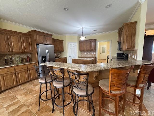 kitchen with range, stainless steel refrigerator with ice dispenser, light stone countertops, decorative light fixtures, and kitchen peninsula