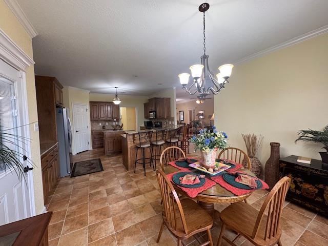 dining space with crown molding and a chandelier