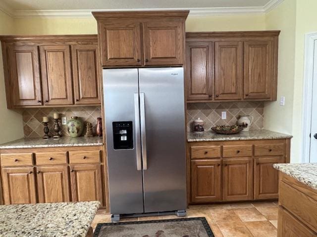 kitchen featuring tasteful backsplash, ornamental molding, stainless steel fridge, and light stone countertops