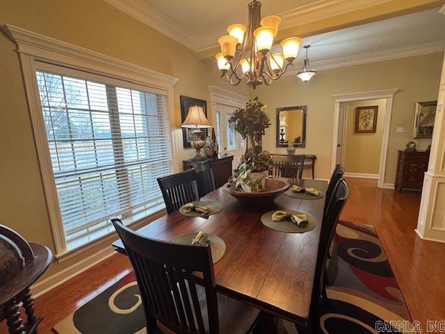 dining space featuring an inviting chandelier, crown molding, and dark hardwood / wood-style floors