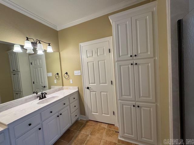 bathroom featuring tile patterned flooring, ornamental molding, and vanity