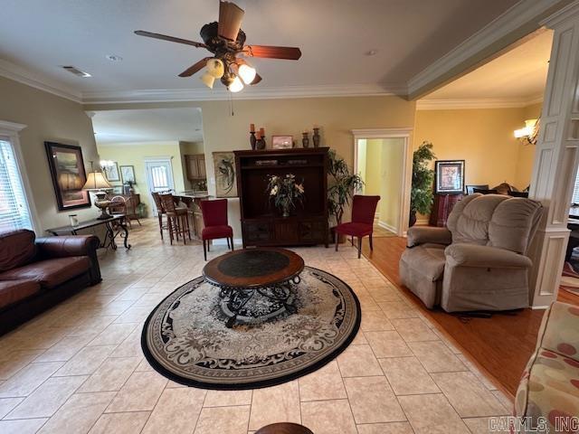 living room featuring light tile patterned floors, crown molding, and plenty of natural light