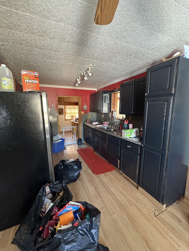 kitchen with stainless steel refrigerator, ornamental molding, sink, and light hardwood / wood-style flooring