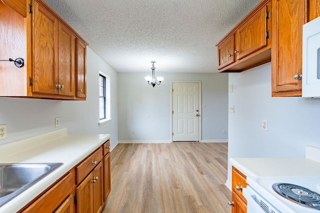 kitchen with pendant lighting, white appliances, a notable chandelier, a textured ceiling, and light wood-type flooring