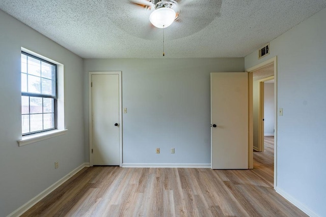 unfurnished room with ceiling fan, a textured ceiling, and light hardwood / wood-style floors