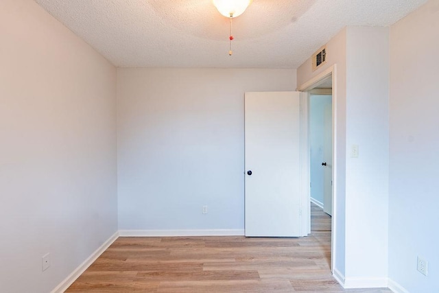 empty room with light hardwood / wood-style floors and a textured ceiling