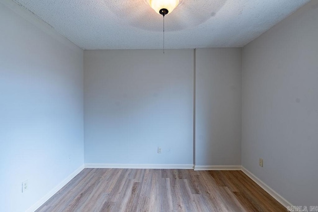 spare room with a textured ceiling and light wood-type flooring