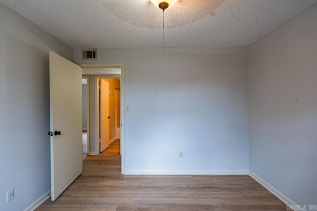 empty room featuring a textured ceiling and light wood-type flooring