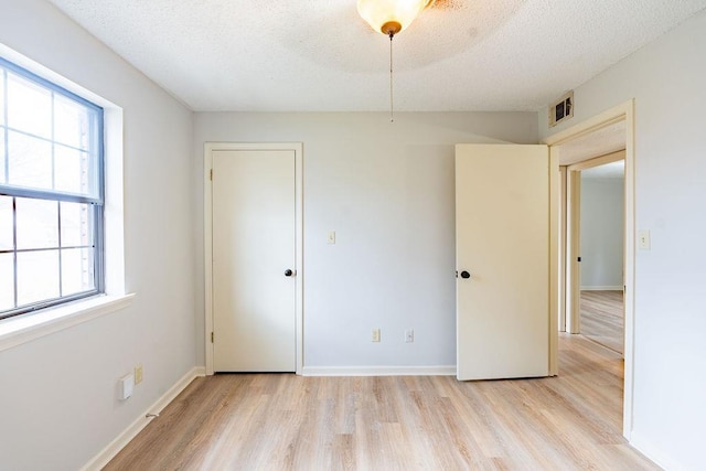 unfurnished bedroom with a textured ceiling and light hardwood / wood-style floors