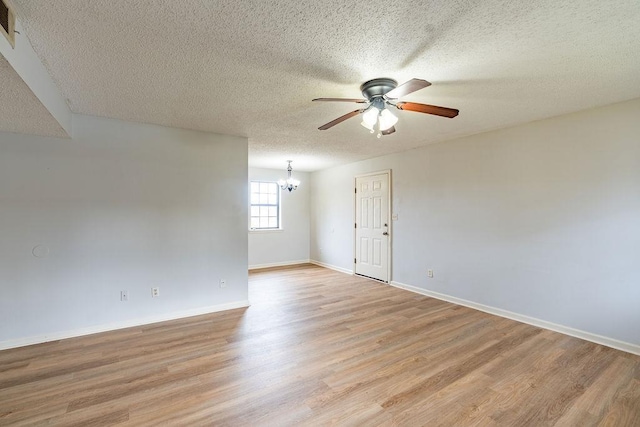 unfurnished room with ceiling fan with notable chandelier, light hardwood / wood-style flooring, and a textured ceiling