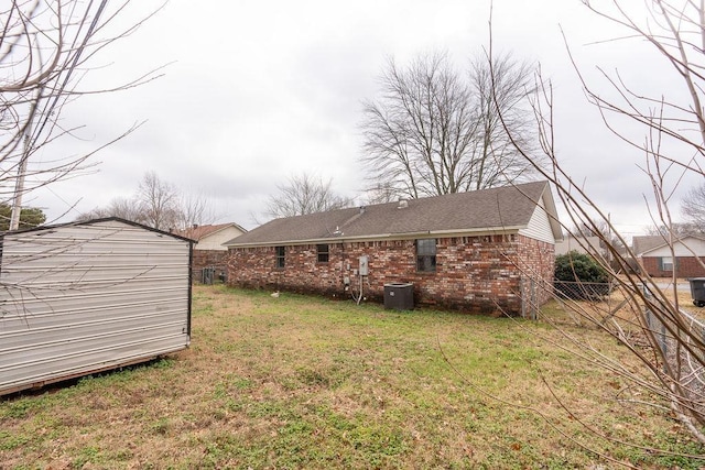 back of house featuring a shed, central AC unit, and a lawn