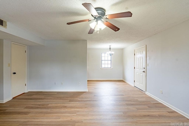 unfurnished room with ceiling fan with notable chandelier, light hardwood / wood-style floors, and a textured ceiling