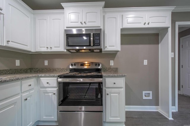 kitchen with appliances with stainless steel finishes, dark hardwood / wood-style flooring, light stone countertops, and white cabinets