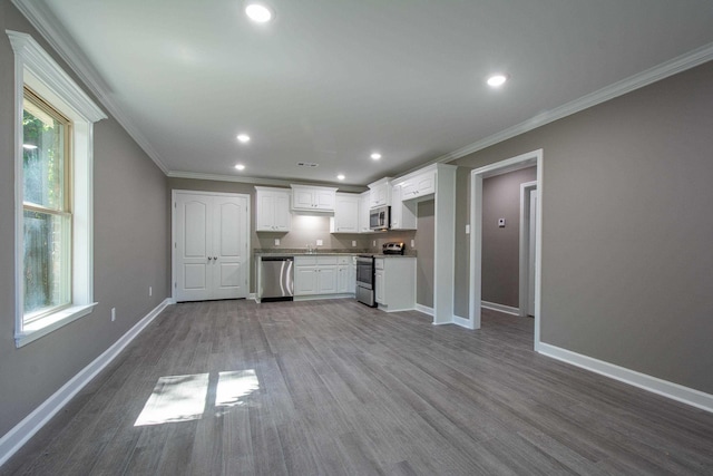 kitchen featuring appliances with stainless steel finishes, white cabinetry, sink, ornamental molding, and light wood-type flooring