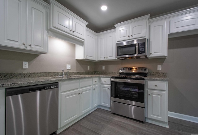 kitchen featuring stainless steel appliances, white cabinetry, light stone countertops, and sink