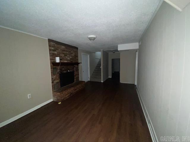 unfurnished living room featuring a fireplace, dark hardwood / wood-style floors, and a textured ceiling