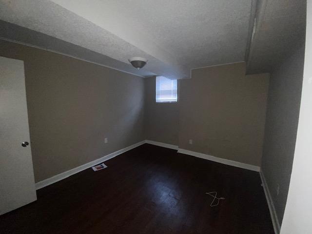 basement with dark hardwood / wood-style floors and a textured ceiling