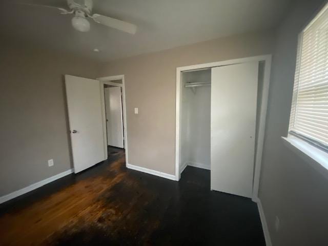 unfurnished bedroom with dark wood-type flooring, ceiling fan, and a closet