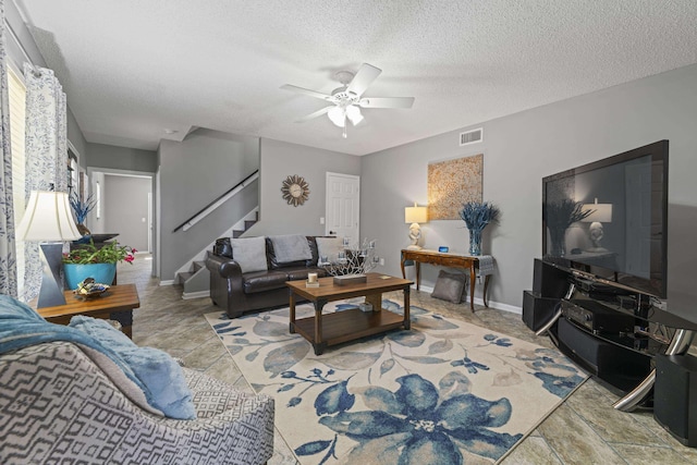 living room featuring ceiling fan and a textured ceiling