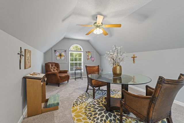 dining area featuring ceiling fan, lofted ceiling, light colored carpet, and a textured ceiling