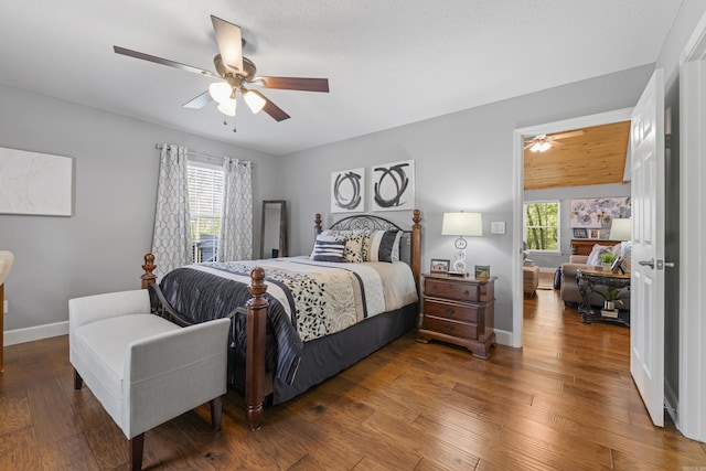 bedroom featuring ceiling fan, dark hardwood / wood-style floors, and multiple windows