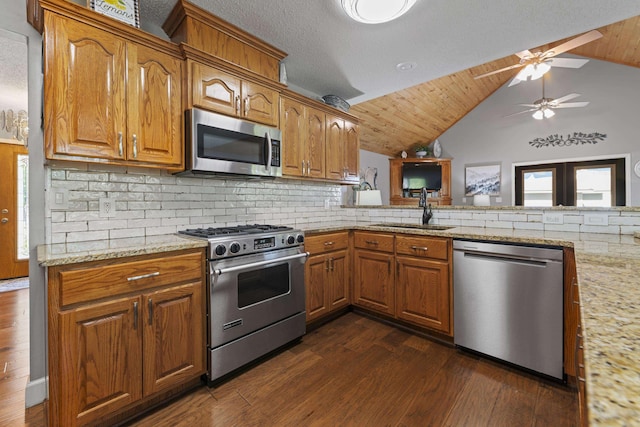 kitchen featuring sink, dark hardwood / wood-style floors, stainless steel appliances, light stone countertops, and decorative backsplash